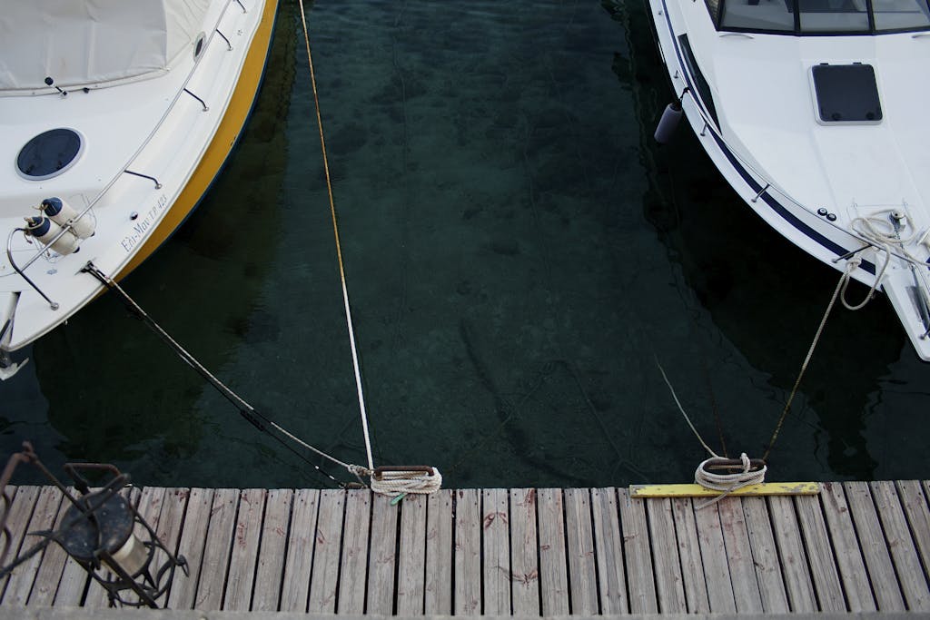 Aerial view of boats docked on crystal-clear waters at a wooden dock in Rodos, Greece.
