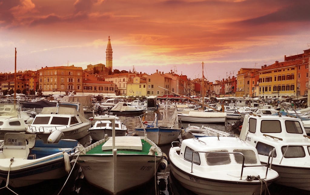 Vibrant sunset over Rovinj harbor with moored boats and historic town skyline.