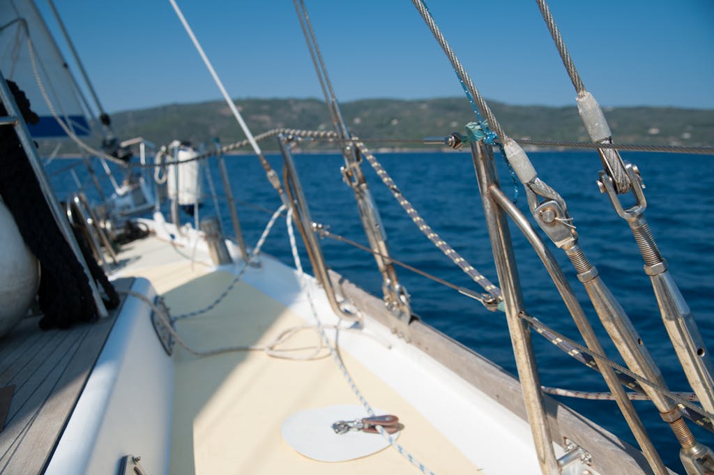 A close-up view of a sailboat deck with nautical ropes and rigging under blue skies.