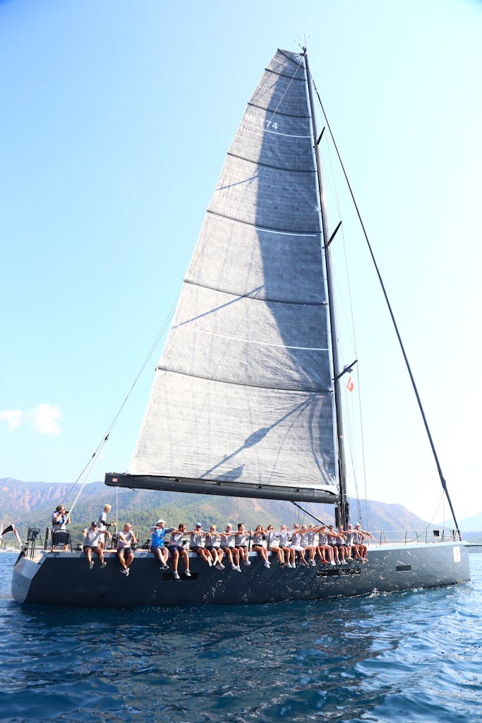 A group of adults enjoying a thrilling sailing experience on a large yacht during the daytime.